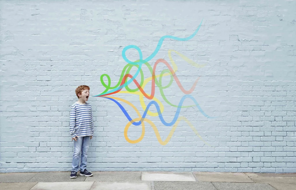 Child standing near wall with colorful doodles