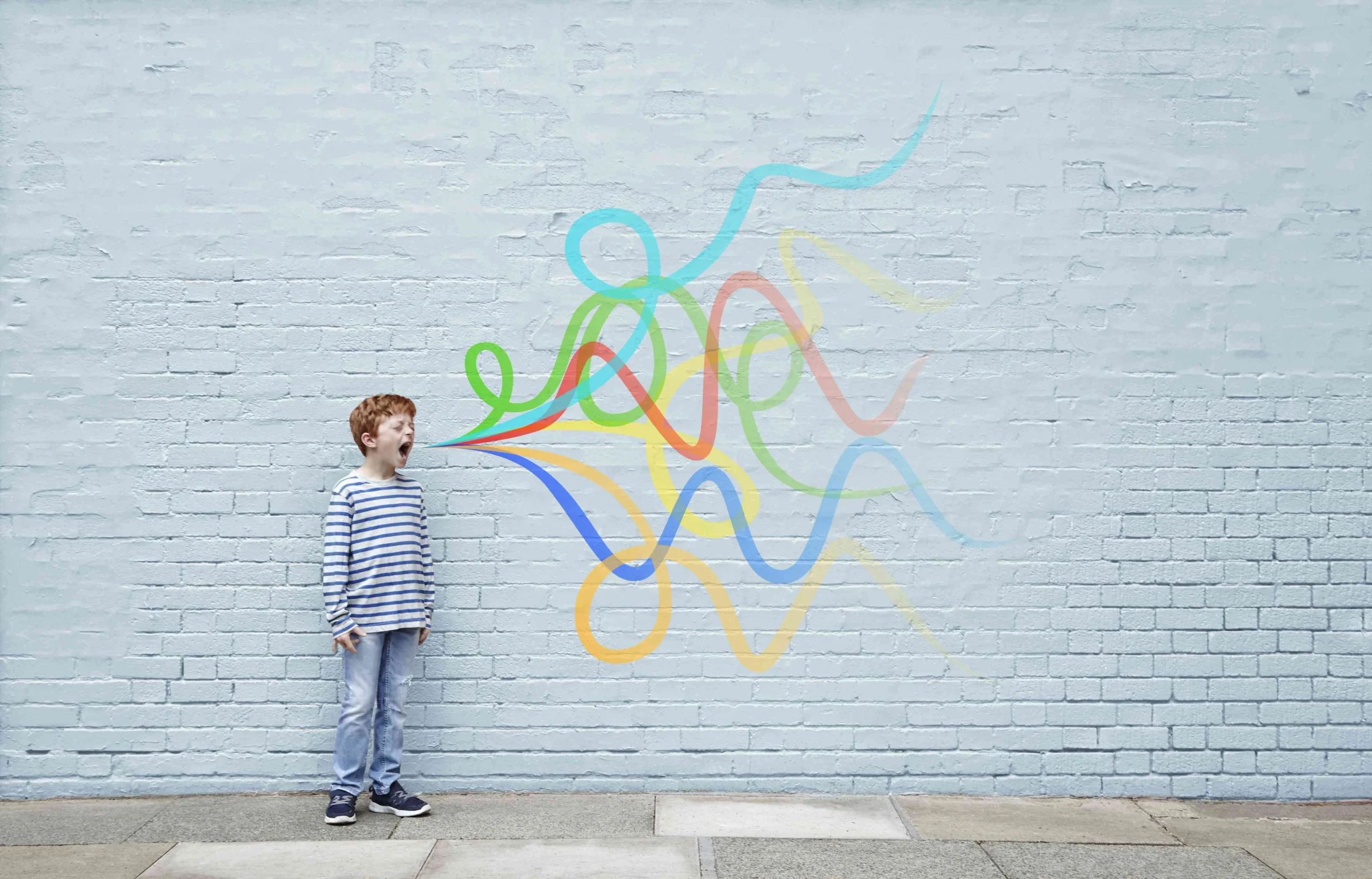 Child standing near wall with colorful doodles