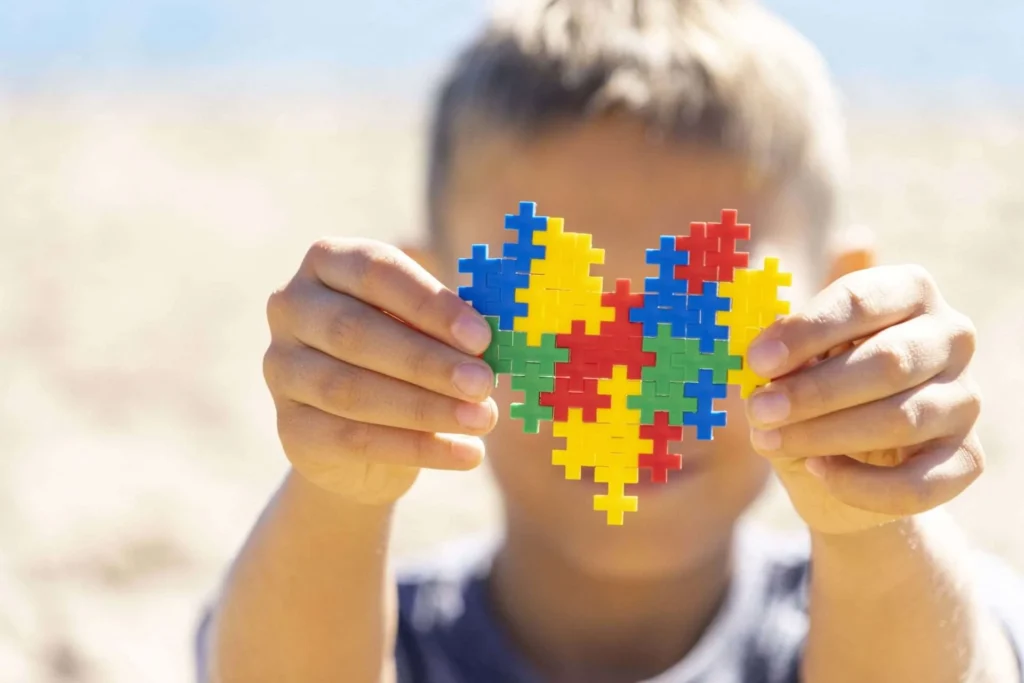 Girl holding colorful puzzle heart shape